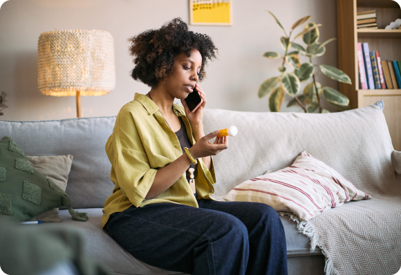 woman on the phone while looking at a medication bottle