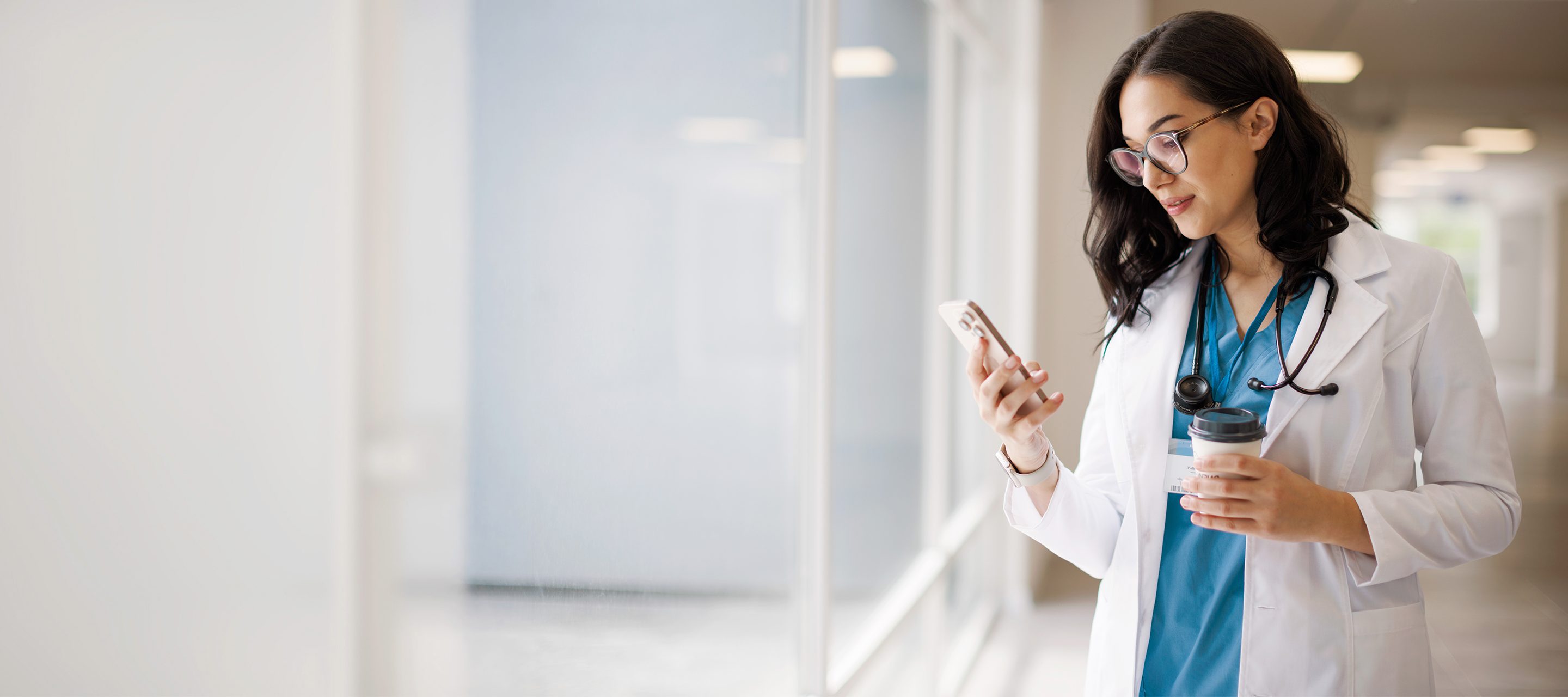 doctor on cell phone holding a coffee