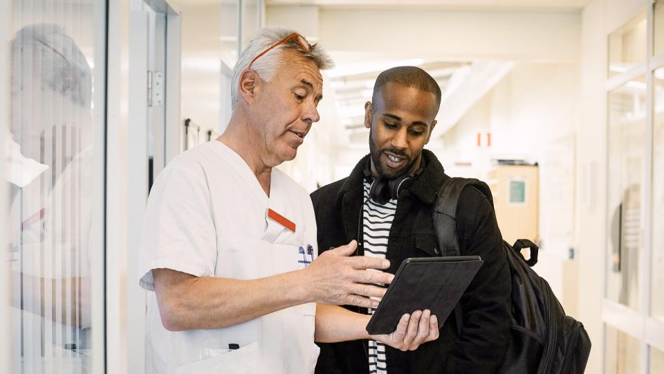 A clinician and his patient review notes on a tablet.