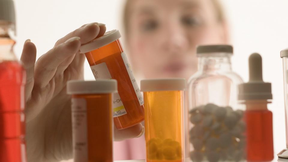 Woman gazing into a crowded medicine cabinet