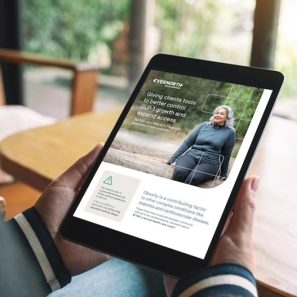 Person holding tablet displaying Evernorth web interface with outdoor scene and text overlay.