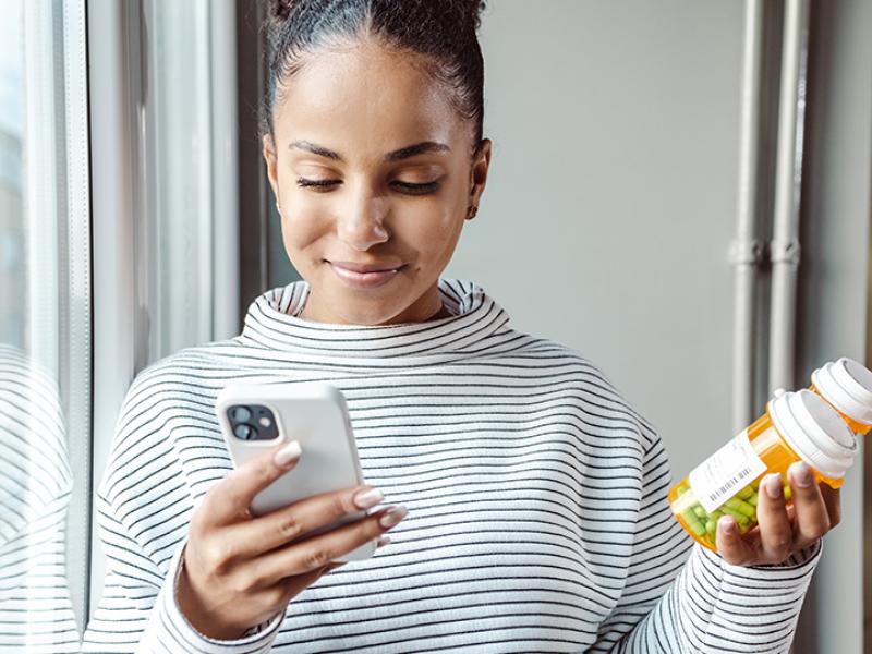 Woman looking at phone and medication