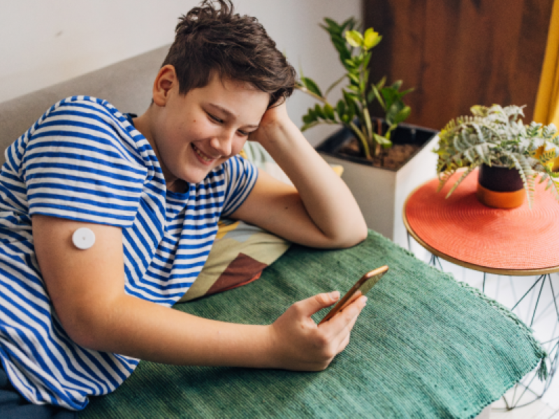young adult with glucose monitor looking at mobile phone