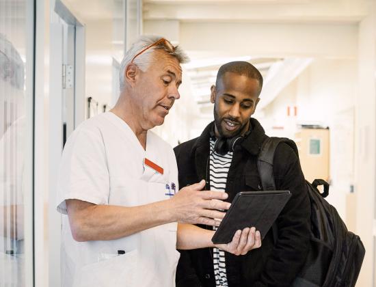 A clinician and his patient review notes on a tablet.