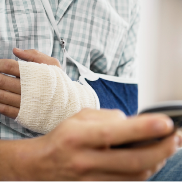 Patient in arm sling holding mobile device for a virtual appointment