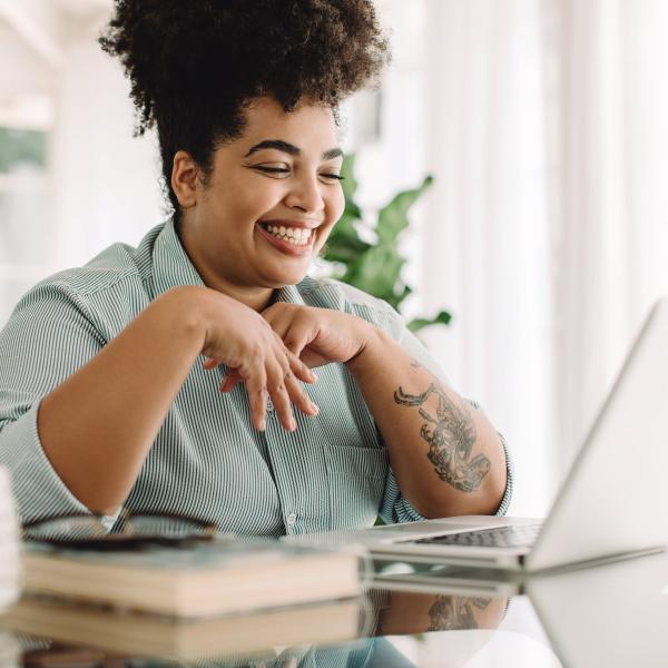 Smiling woman looking at her open laptop computer.