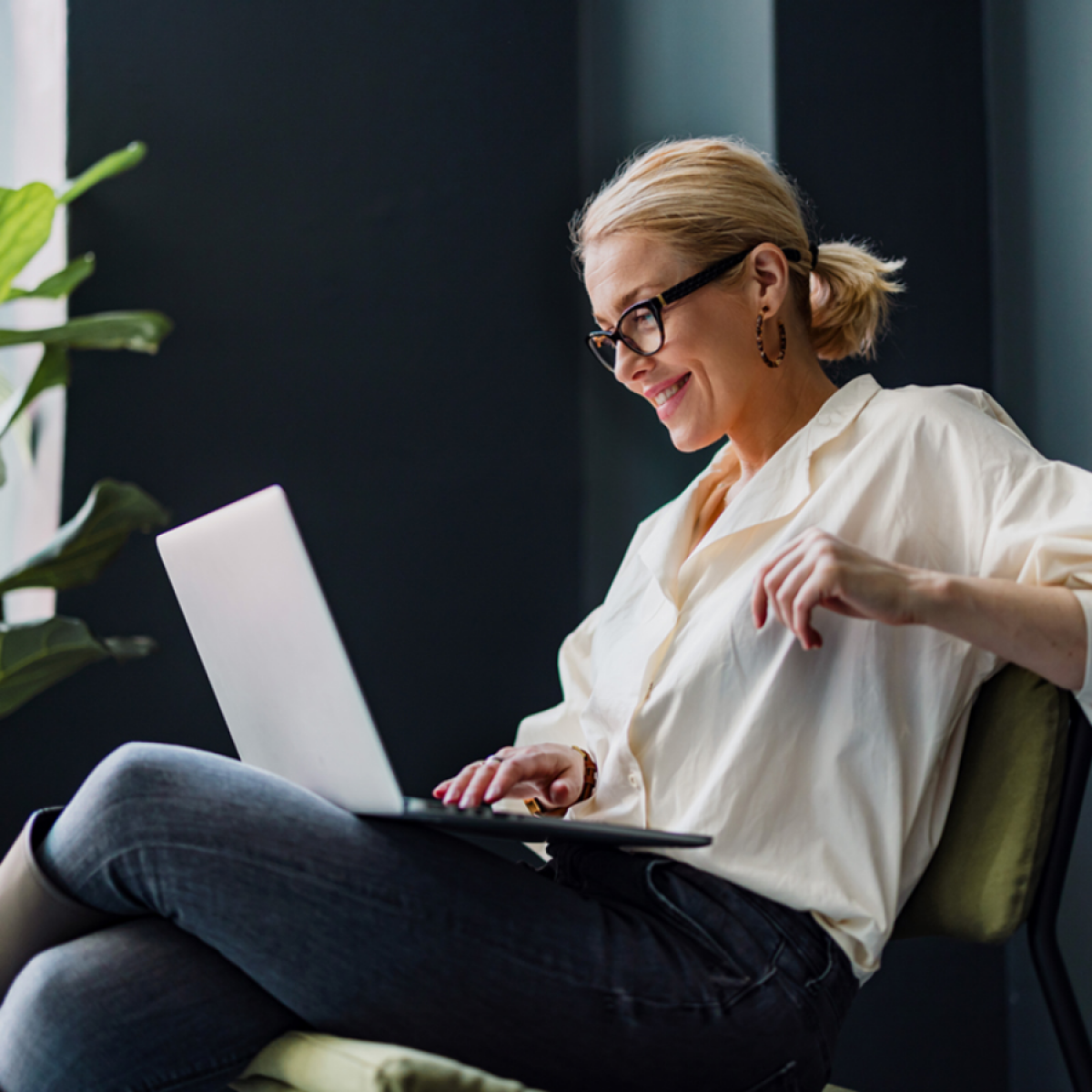 Woman with eyeglasses smiling looking at laptop